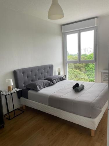 a bedroom with a large bed with a large window at appartement mérignac avec parking in Mérignac