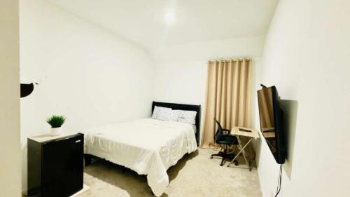 a white bedroom with a bed and a television at Luxe Haven in Richmond