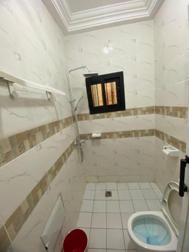 a white bathroom with a toilet and a window at Lita résidence in Yaoundé