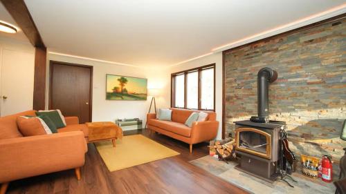 a living room with a brick wall and a fireplace at Nemandua Catskills: Hot Tub+Fire Pit+Pool Table+EV in Lanesville
