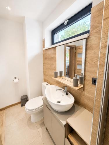 a bathroom with a sink and a toilet and a window at M3-Apartmány in Martin