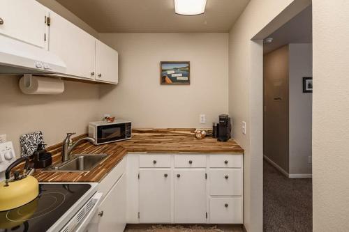 a kitchen with white cabinets and a sink and a microwave at Historic Downtown Deco Queen Studio in Anchorage