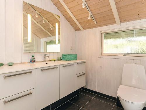 a bathroom with a toilet and a sink and a window at 4 star holiday home in Græsted in Græsted