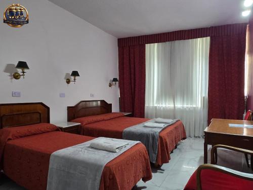 a hotel room with two beds and a table at Hotel Tres Sargentos in Buenos Aires