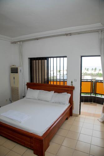 a bedroom with a large bed with white sheets at Atlantic Beach Hôtel Bénin in Cotonou