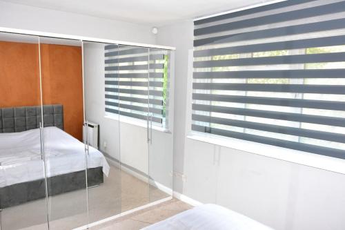 a bedroom with a bed and a window with blinds at Magic House- London in Plumstead