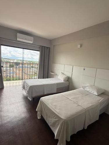 a hotel room with two beds and a large window at Hotel Quartzo in Cristalina
