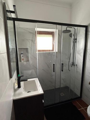 a bathroom with a glass shower and a sink at Casa dos Cândidos in Alagoa