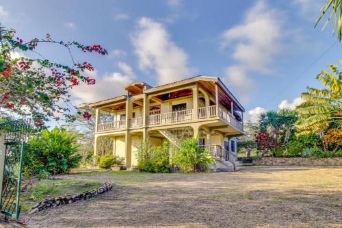 een geel huis met een balkon en bomen bij Villa Maya in San Ignacio