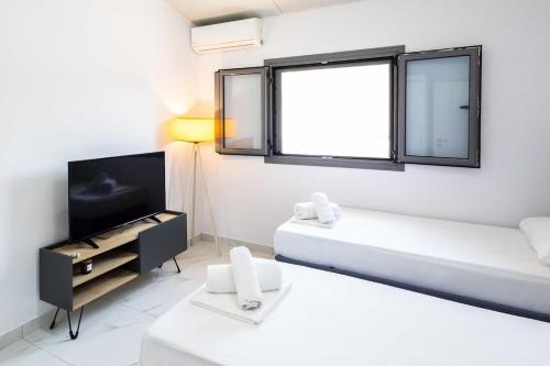 a white room with two beds and a window at Domus Villa in Ermioni