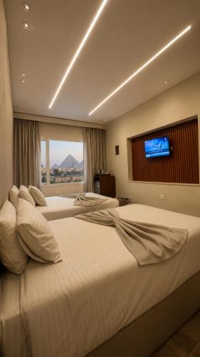 two beds in a hotel room with a flat screen tv at Cacillion Pyramids View in Cairo