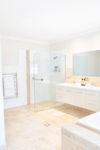 a white bathroom with a shower and a sink at The Gables Berry in Berry