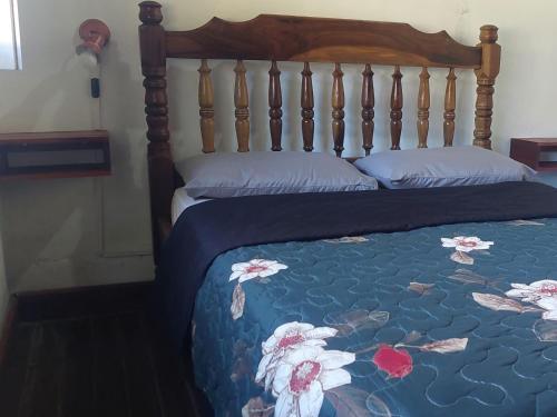a bed with a blue comforter with flowers on it at El RINCÓN in Oberá