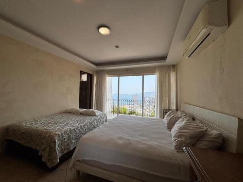 a bedroom with two beds and a large window at Casa las Palmas in Acapulco