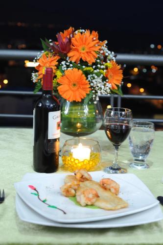 a table with a plate of food and a bottle of wine at Hotel San José Plaza in Bucaramanga