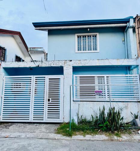a white building with a gate and a garage at MiKasa Azul Transient House in Cabuyao