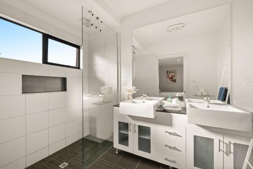 a white bathroom with two sinks and a shower at The Islander in Ventnor