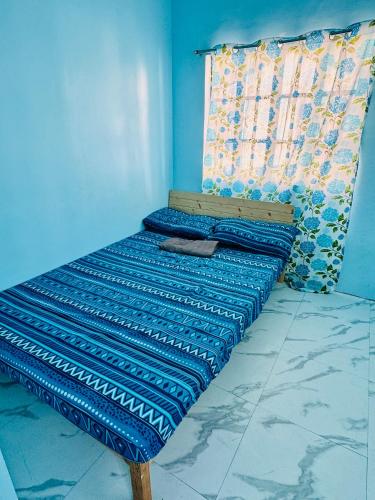 a bed in a room with a blue wall at MiKasa Azul Transient House in Cabuyao
