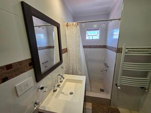 a bathroom with a sink and a shower with a mirror at Departamentos Atlantic in Monte Hermoso