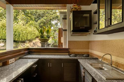 a kitchen with a sink and a large window at Bumbung Sari Villa in Ubud