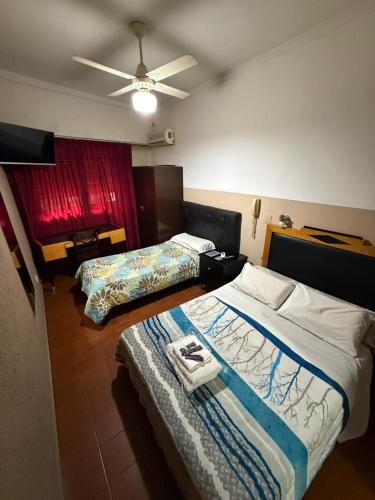 a hotel room with two beds and a ceiling fan at Hispano Argentino in Buenos Aires