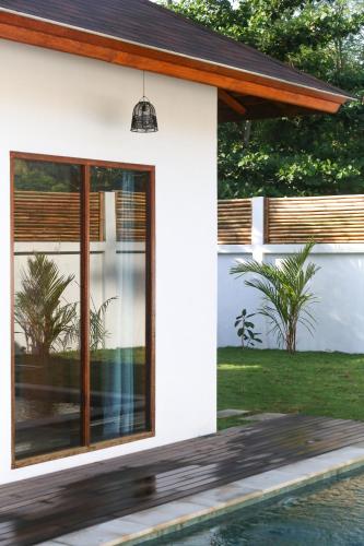 a house with large windows next to a swimming pool at Markisa Villas - Spacious Private Pool Homes on Gili Air in Gili Islands