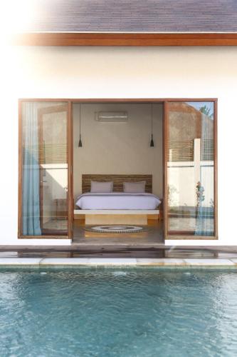 a bedroom with a bed next to a swimming pool at Markisa Villas - Spacious Private Pool Homes on Gili Air in Gili Islands