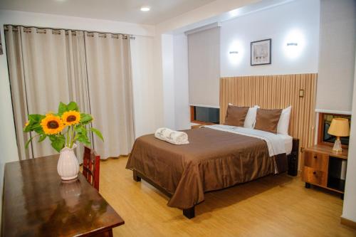 a bedroom with a bed and a table with a vase of flowers at HOTEL TERRANOVA Abancay in Abancay