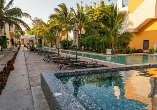 a swimming pool with chairs and umbrellas next to a building at Telchac 3 bedrooms, pool and beach in Telchac Puerto