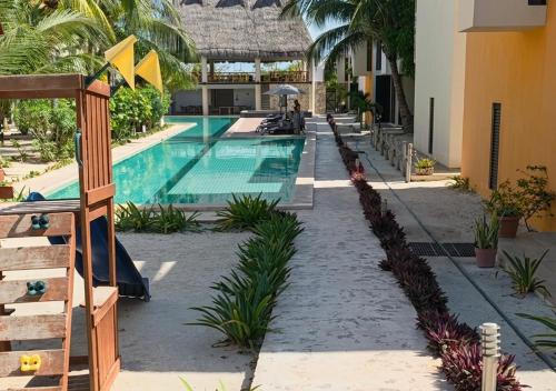 a swimming pool in a resort with palm trees at Telchac 3 bedrooms, pool and beach in Telchac Puerto