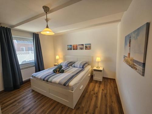 a bedroom with a bed and two lamps and a window at Ferienhaus Seeschwalbe in Tossens