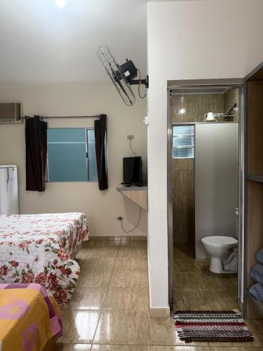 a bedroom with a bed and a bathroom with a toilet at Recanto dos Amigos Suítes CANTÃO DO INDAIA in Bertioga