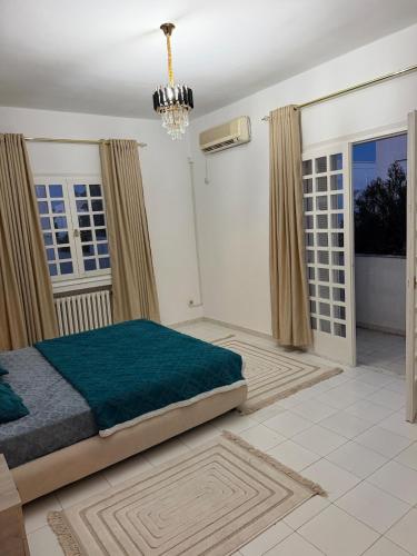 a bedroom with a bed and a chandelier at Villa Marsa in Dar el Haj Ahmed Souid