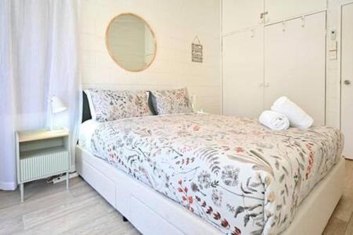 a white bedroom with a bed and a mirror at Beachfront 1BR Loft. Surf-Café-Unwind in Marcoola