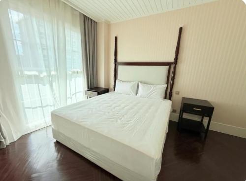 a bedroom with a large bed and a large window at Pattaya Private Beach - Grand Florida Beachfront Condo Resort in Na Jomtien