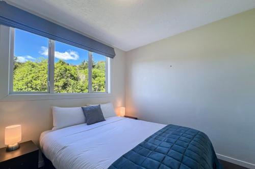 a bedroom with a bed and a large window at Selwyn Heights in Akaroa