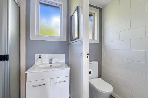 a white bathroom with a toilet and a sink at Selwyn Heights in Akaroa