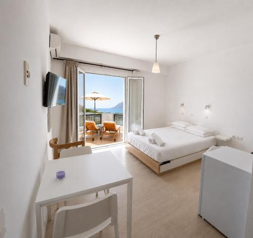 a white room with a bed and a table and a bed and a window at Orama Studios in Plakias