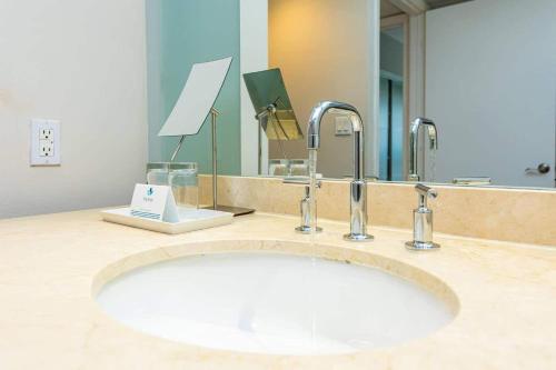 a bathroom sink with two faucets and a mirror at Oceanview Apt Marenas Resort, Direct Beach Access! in Sunny Isles Beach