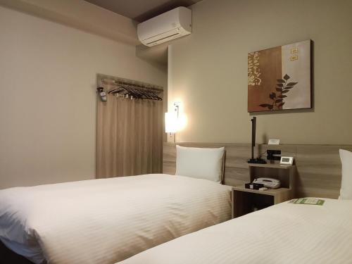 a hotel room with two beds and a window at Hotel Route-Inn Hamada Ekimae in Hamada