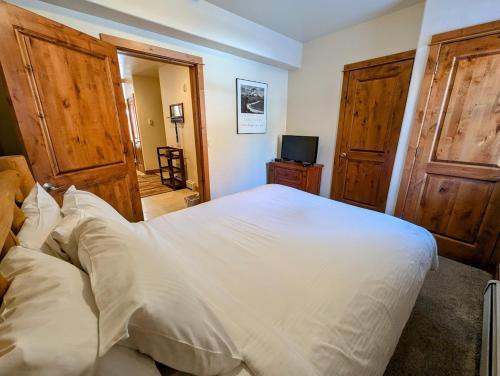 a bedroom with a large white bed and wooden doors at Antlers Gulch 501 by SummitCove Lodging in Colorado in Keystone