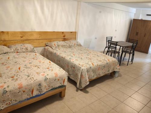 a bedroom with two beds and a table and chairs at Lofts en el Corazon de Coatepec Veracruz in Coatepec