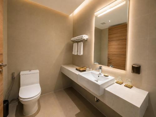 a bathroom with a sink and a toilet and a mirror at Flamingo Cát Bà Sea Residence , Sky Villa Premier Ocean View King Bed in Hai Phong