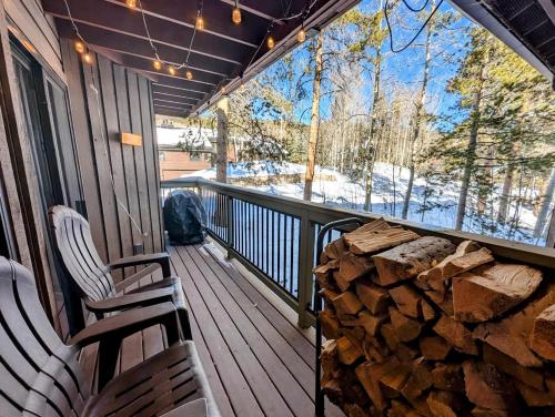 a porch with two chairs and a pile of logs at Wild Irishman 1059 by SummitCove Lodging in Colorado in Keystone
