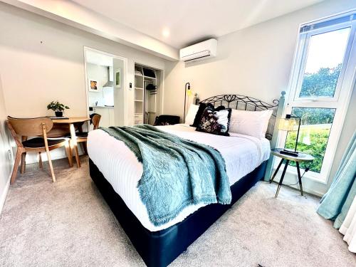 a bedroom with a bed and a table and a window at Stylish Lyttelton Studio Free Parking in  Lyttelton
