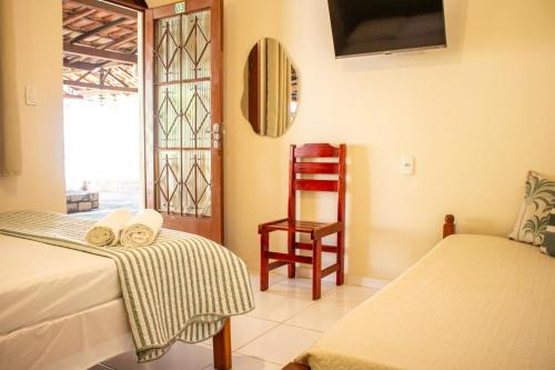 a room with two beds and a chair and a window at Pousada Refúgio Serrano in Serra Negra