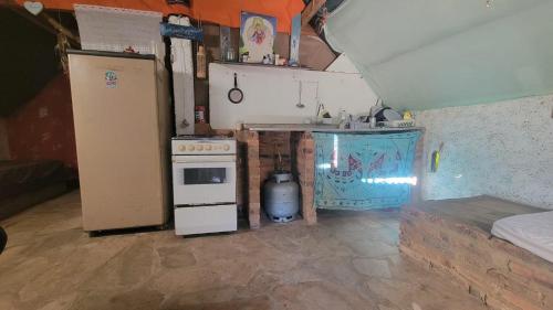a small kitchen with a stove and a refrigerator at Vila Druida Spa Caipira in São Thomé das Letras