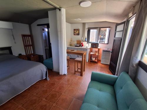 a bedroom with a blue couch and a kitchen at Hospedaje El Rancho in Castillos