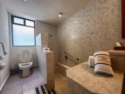 a bathroom with a toilet and a sink and a tub at Hotel Misión Comanjilla in Comanjilla