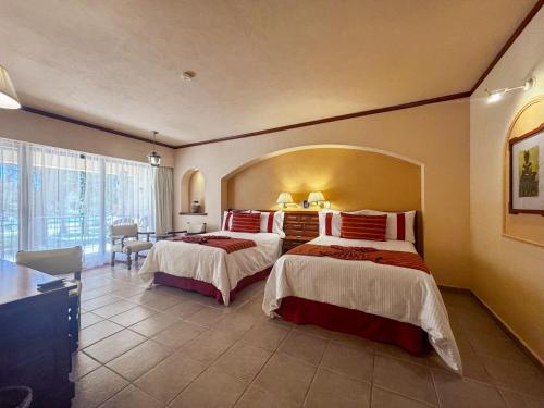 a hotel room with two beds and a desk at Hotel Misión Comanjilla in Comanjilla